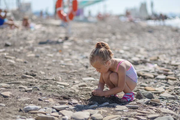 Ragazza carina che gioca con i ciottoli sulla spiaggia — Foto Stock