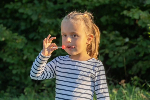 Linda niña comiendo piruleta al aire libre — Foto de Stock