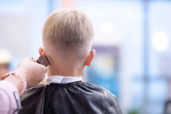 Friseur schneidet Jungen Haare mit Haarschneidemaschine auf den Kopf. — Stockfoto