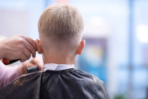 Cabeleireiro corta cabelos com clipper na cabeça dos meninos . — Fotografia de Stock