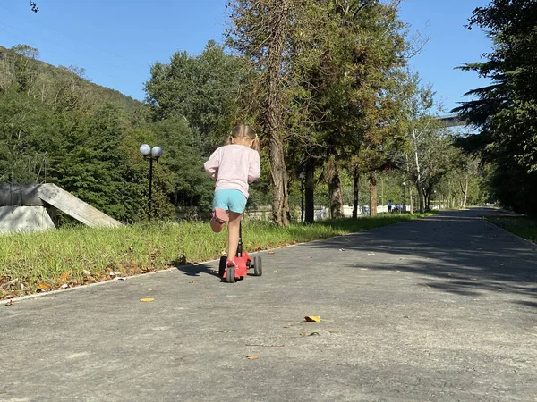 공원에서 스쿠터를 타고 있는 젊은 여자 — 스톡 사진