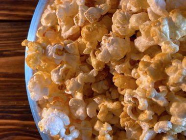 Tahta arka planda cam kasede patlamış mısır.