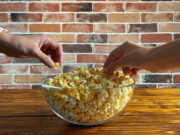 Закрыть руки и взять попкорн из миски
.