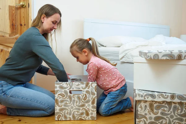 Mutter und kleine Tochter legen Kleidung in Karton zusammen — Stockfoto