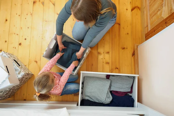 Madre e hija pequeña poniendo la ropa a la caja de la tarjeta juntos — Foto de Stock