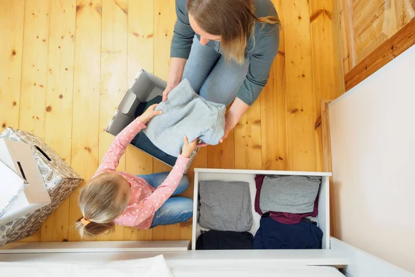 Madre e hija pequeña poniendo la ropa a la caja de la tarjeta juntos —  Fotos de Stock