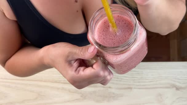 Young woman in sportswear drinking strawberry and banana smoothie — Stock Video