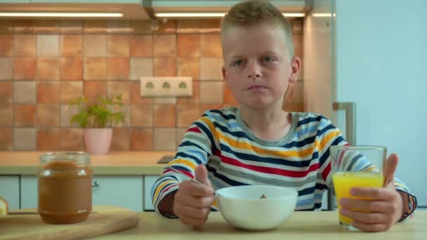 Hongerige jongen eet cornflakes met melk bij het ontbijt — Stockvideo