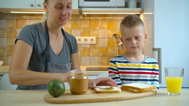 Ongelukkige jongen wil geen gezonde pindakaas eten bij het ontbijt. — Stockvideo