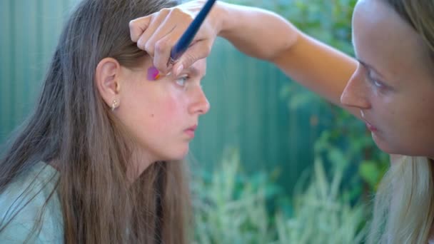 Dibujo de artista en la cara adolescente, preparándose para el carnaval — Vídeo de stock