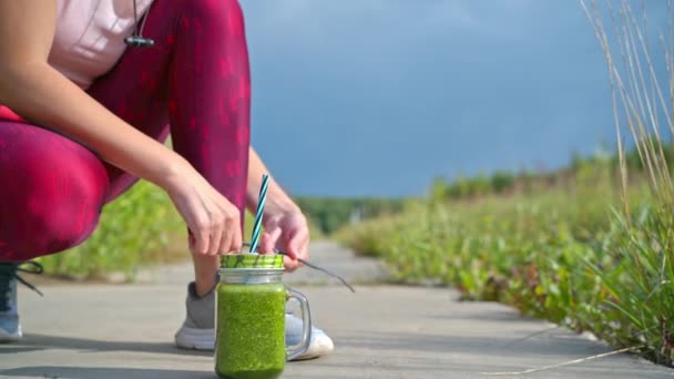 Vrouw loopt buiten met groene detox smoothie — Stockvideo
