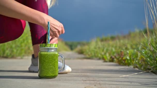 Woman running outdoors with green detox smoothie — Stock Video