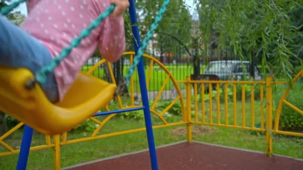 Kleines Mädchen lächelt und schaukelt auf Spielplatz — Stockvideo