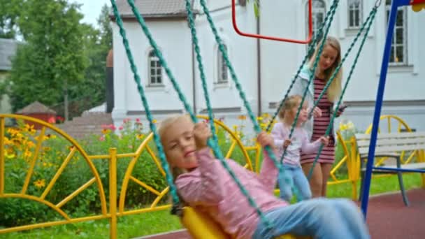 Mãe com duas filhas balançando no playground — Vídeo de Stock