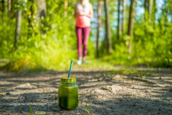 Woman running outdoors with green detox smoothie — Stock Photo, Image