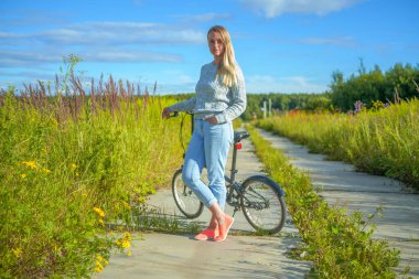 Kırsal alanda bisiklet süren mutlu, gülen bir kadın.