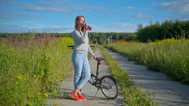 Jonge vrouw verblijft met fiets en drinkwater — Stockvideo