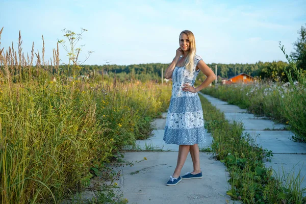 Blond kvinna i lång klänning poserar i landsbygden landskap — Stockfoto