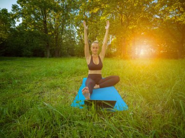 Kadın, dizüstü bilgisayarla yoga öğretiyor ve pratik yapıyor.