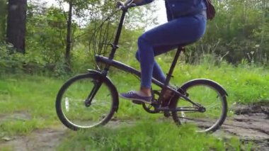 Kırsal yolda bisiklet süren kot pantolonlu bir kadın.