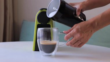 Taze süt, cam bardağa espresso ile doldurulur ve ev yapımı latte yapılır. Kahve hazırlama konsepti, cafe tarzı içecekler, kremsi dokular ve rahat ev yapımı deneyimler..