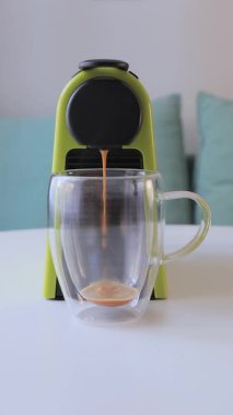 Modern bir kahve makinesinden şeffaf bir cam fincana taze espresso dökülüyor. Güne aromatik kafein takviyesiyle mükemmel bir başlangıç..