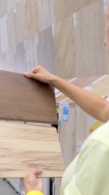 Hırdavatçıda plastik döşeme örnekleri tutan kadına yakın çekim, iç tasarım için doku ve renkleri karşılaştırma. Ev geliştirme, yenileme, inşaat malzemeleri, döşeme seçenekleri ve modern DIY alışveriş yaşam tarzı kavramı.