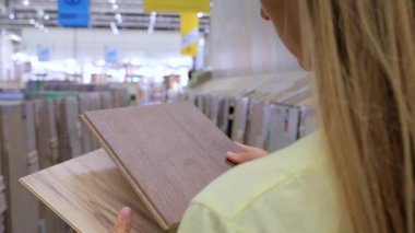 Hırdavatçıda plastik döşeme örnekleri tutan kadına yakın çekim, iç tasarım için doku ve renkleri karşılaştırma. Ev geliştirme, yenileme, inşaat malzemeleri, döşeme seçenekleri ve modern DIY alışveriş yaşam tarzı kavramı.