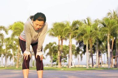 Yorgun kadın atlet açık havada yol ve Bahçe arka plan ayakta zor çalışmadan sonra bir ara verdi