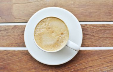 Bir fincan kahve, ahşap masa, üst manzara.