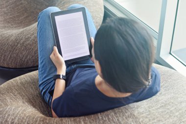 Genç bir kadın omuz görünümü e-kitap dijital cihaz üzerinde okuma