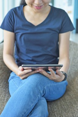 O kanepede rahatlatır gibi bir e-kitap onun tablet bilgisayarda mutlu genç kadının