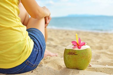 Genç kadın ile Hindistan cevizi suyu yaz tatile sahilde rahatlatıcı.