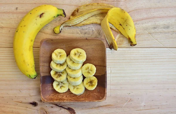 Очищенный и нарезанный банан, лежащий на деревянной тарелке — стоковое фото