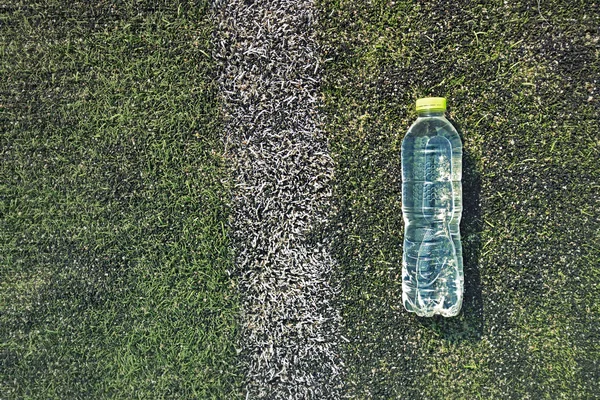 Plastic bottle on a football field with white line — Stock Photo, Image