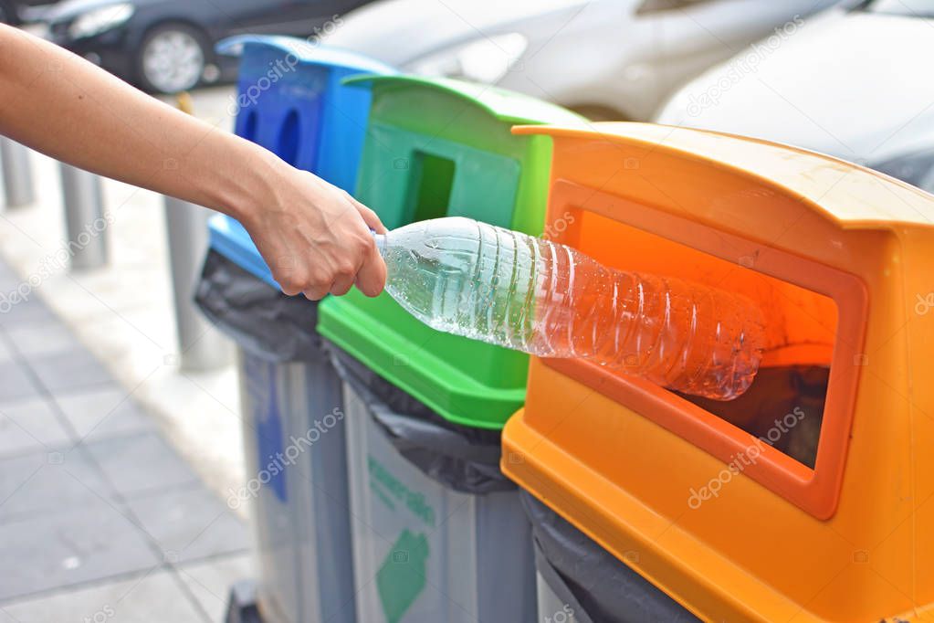 Woman throwing plastic bottle into recycle bin