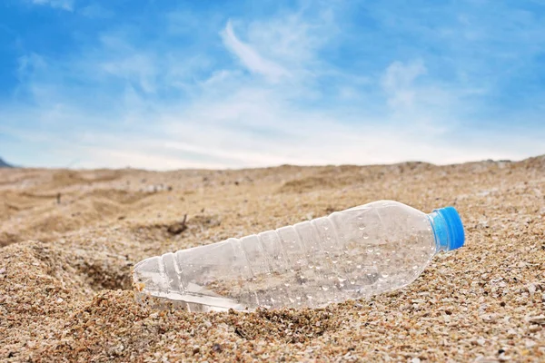 Plastic bottle of water in sand on tropical sandy beach