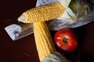 Tahta bir izin üzerine domates ve mısır.