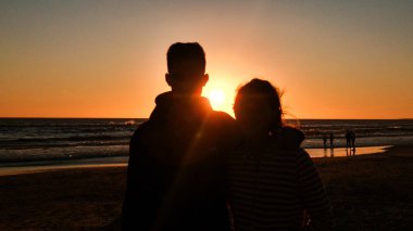 Bir plaj günbatımı arka plan ile Gölge çift