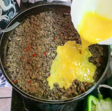 bir kapaklı bir tencerede soğan, kırmızı biber, yumurta ve baharat ile kıyma pasta