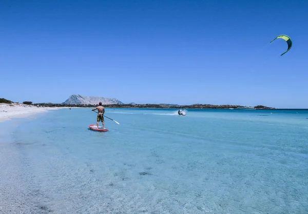 San Teodoro - La Cinta Beach - 2017 Temmuz - genç bir atlet kürek kürek kristal deniz Sardunya, su kitesurfer slaytlarda onun yanında iken ayağa üzerinde