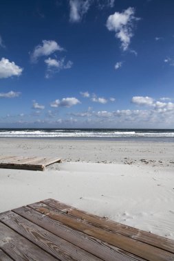 Boardwalk kış denizin içinde. Yalan bitmiş sezon yalnızlık içinde terk edilmiş ahşap platformlar üzerinde beyaz kum aceleci deniz tarafından taşındı,