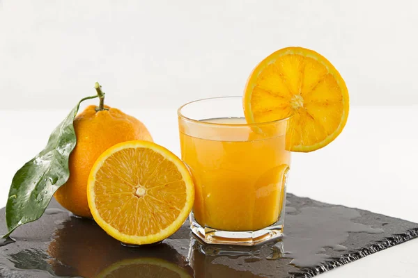An inviting glass full of orange juice with orange slice on the