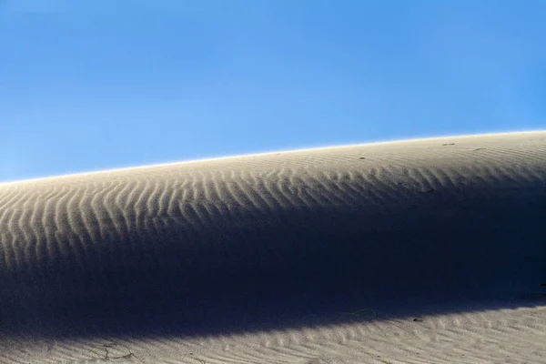 Shadow play on a sand dune with backlight effect and the sun shi