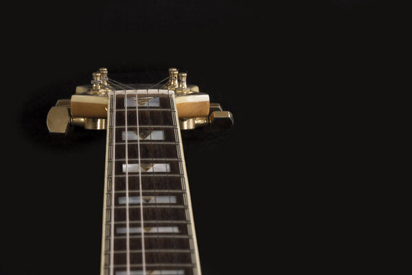 Vintage archtop guitar in natural maple close-up high angle view on black background, rosewood fingerboard with frets and fret markers detail in selective focus