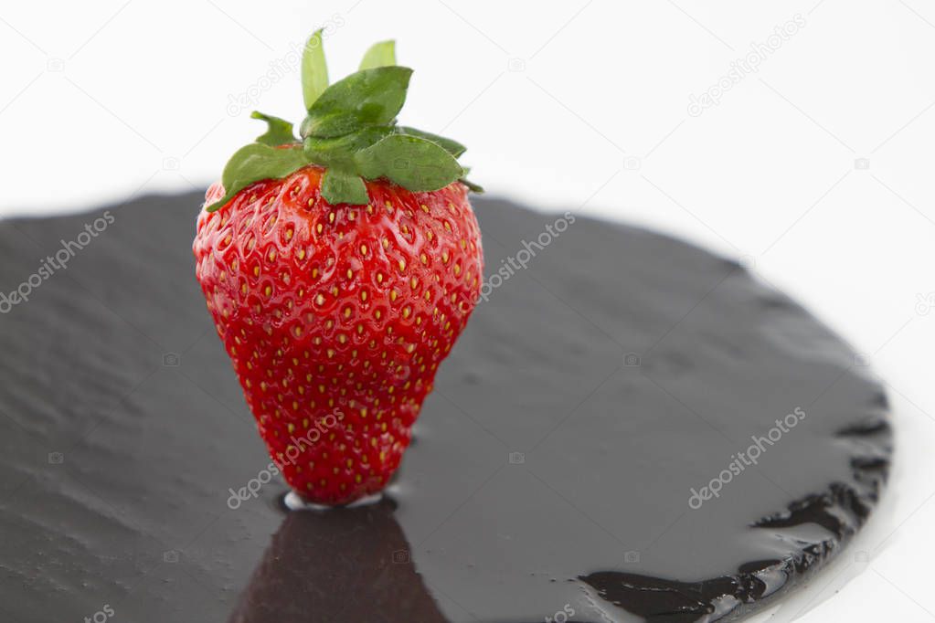 Close-up of a strawberries isolated on a wet round slate plate o