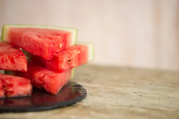 Triangular slices of watermelon overlaid on a black plate of wet slate in selective focus for copy space Stock Photo