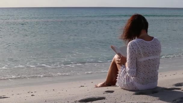 坐在海边的年轻女子在黎明时分望天 穿着白色蕾丝连衣裙 白色内衣 — 图库视频影像