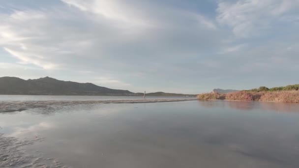 在靠近大海的一个泻湖的半空中拍摄 童话般的日落风景 背景是山的轮廓 背光是太阳 色彩平淡 — 图库视频影像