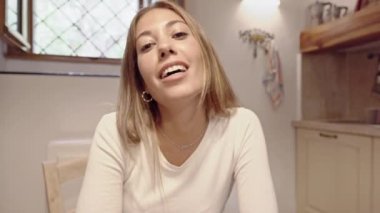 Kameraya bakıp gülümseyen ve konuşan hoş, genç, beyaz bir kadın Coronavirus salgını için çevrimiçi teknoloji ile yapılan yeni bir konferans.